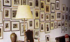 a loose gathering of black and white photographs makes a dramatic statement on the white painted wall